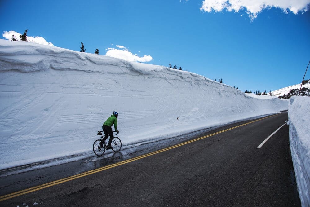 A cyclist takes on the challenge of a fully plowed Trail Ridge Road in Rocky Mountain National Park, Colorado.